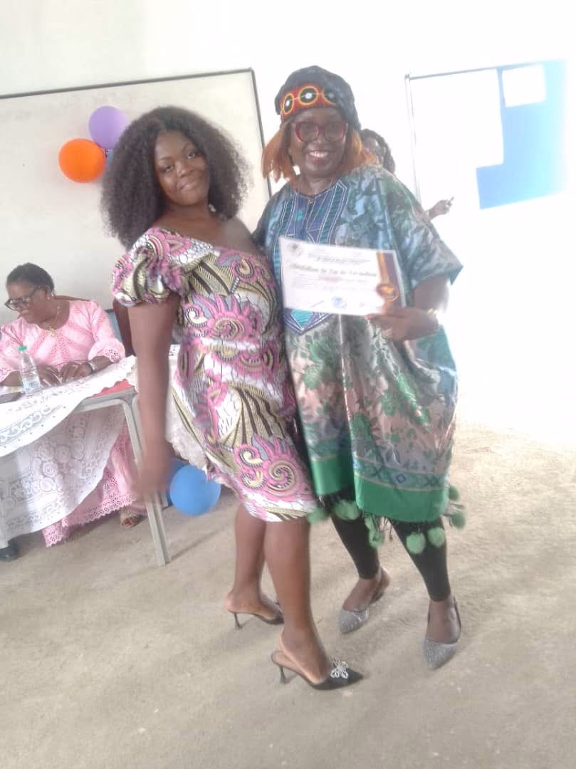 Une lauréate pose avec une invitée en tenue traditionnelle qui tient son attestation de fin de formation.